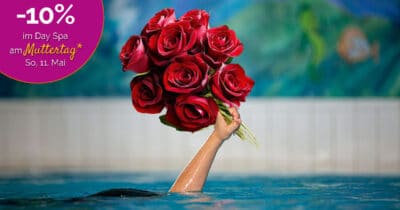 Eine Hand ragt aus dem Wasser eines Schwimmbeckens und hält einen großen Strauß roter Rosen in die Höhe. Links oben im Bild steht in einem violetten Kreis: „–10 % im Day Spa am Muttertag* So, 11. Mai“. Im Hintergrund ist eine bemalte Wand mit Arielle-Motiven zu sehen.